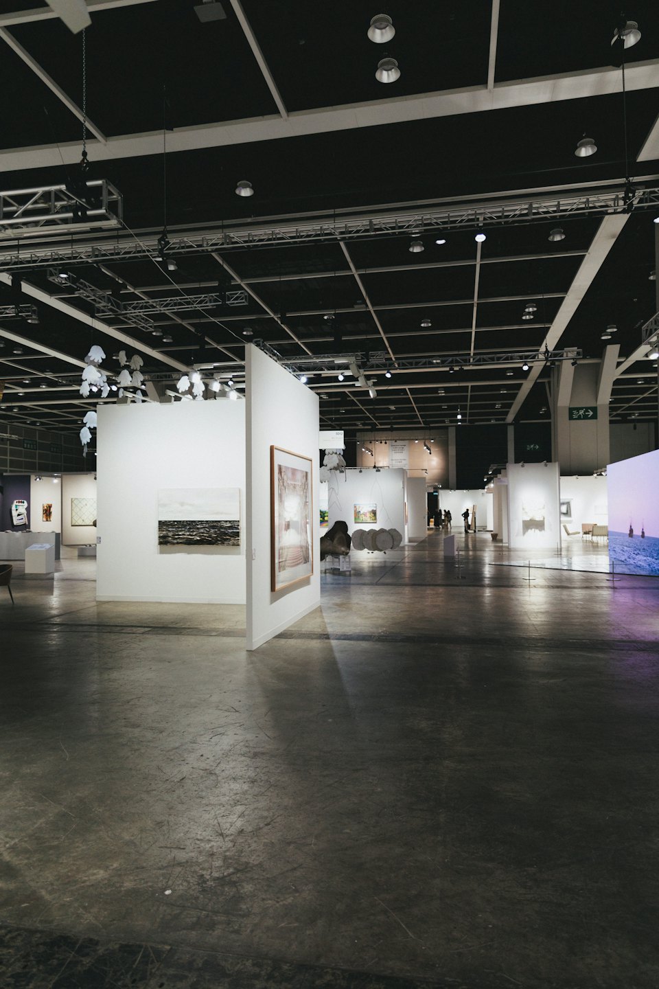 Visitantes pasean por una galería de arte moderno con paredes blancas.